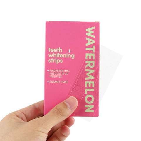 Lucid Bite Watermelon tanden whitening strip die door een hand wordt vastgehouden voor de roze verpakking.