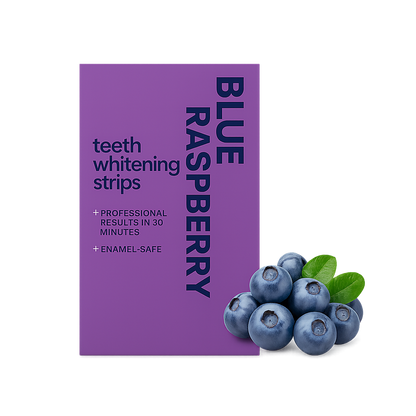 Paarse verpakking van blue raspberry teeth whitening strips met donkere blauwe belettering, vergezeld van blauwe bessen en groene blaadjes als representatie van de smaak, op een egale witte achtergrond.
